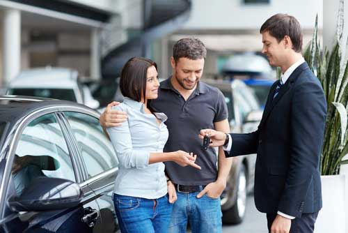 Man and woman receiving keys to their new car.